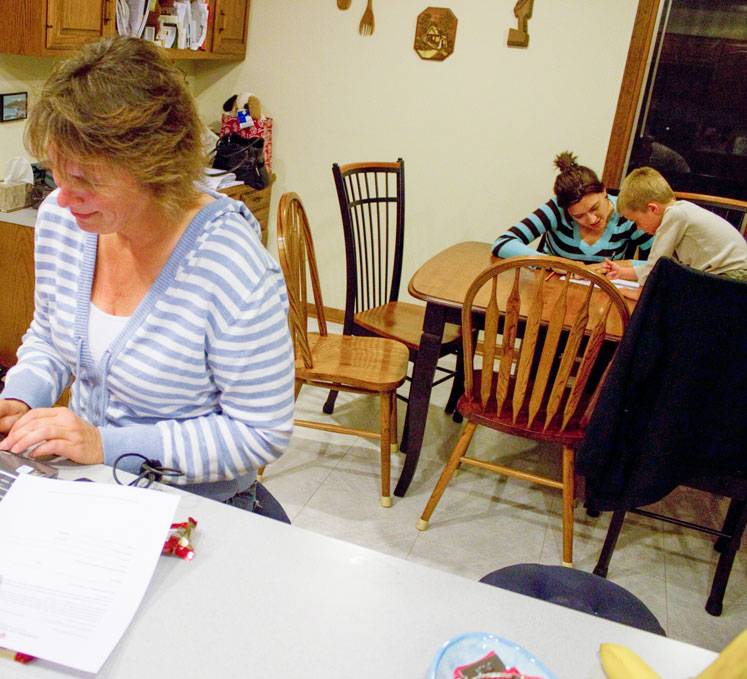 A mother and her children work on schoolwork in the kitchen