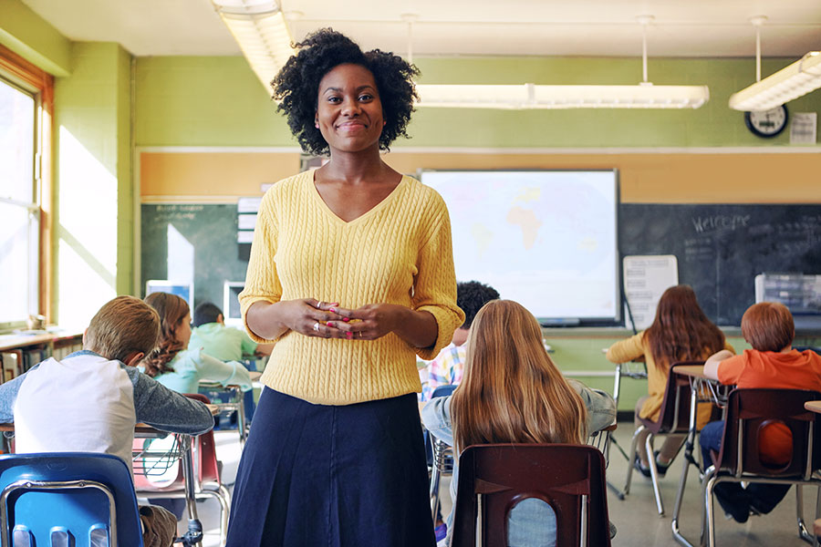 Teacher in yellow sweater standing in classroom