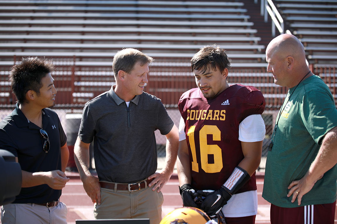 School of Public Health faculty members Kei Kawata and Jon Macy, left and second from left, discuss data with Bloomington North High School football player Noah Ponce, second from right, and School of Education faculty member Jesse Steinfeldt (Photo Credit: Emma Witzke)