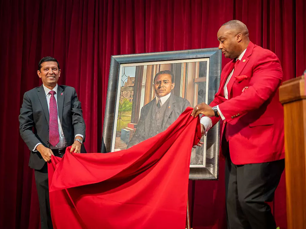 From left, Provost Rahul Shrivastav and Kappa Alpha Psi Grand Polemarch Jimmy McMikle unveil a portrait of Elder Watson Diggs, IU School of Education's first Black alumnus.