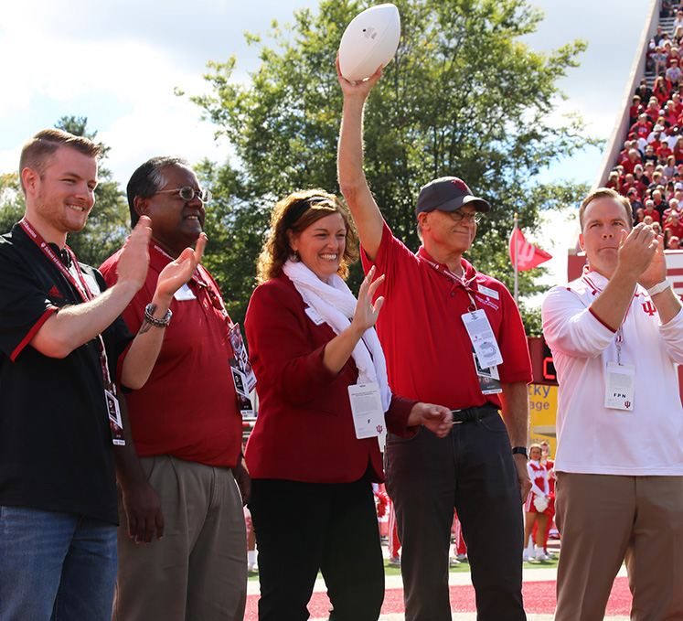 Dean Mason celebrates receiving the game ball during a football game sponsored by the School of Education
