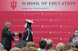 Dean Gerardo Gonzalez presents a graduate with her diploma.