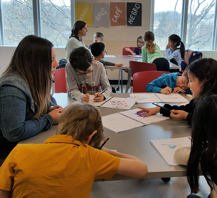 Pre-service teacher Christie Hanna, left, and Trinidad Valdes, near window, assist students in the Spanish Through Art program