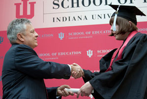 Dean Gerardo Gonzalez hands a diploma to one of the IU School of Education's newest graduates.